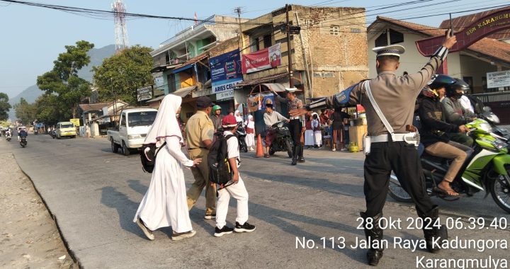 Anggota Lantas Polsek Kadungora Polres Garut Membantu Menyebrangkan Anak Sekolah sebagai bentuk Pelayanan Polri kepada Masyarakat.