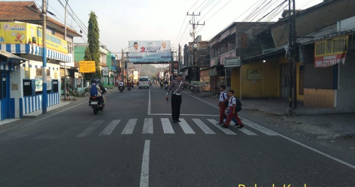 Personil Unit Lantas Polsek Kadungora Polres Garut memberikan pelayanan kepada masyarakat membantu menyeberangkan Anak Sekolah.